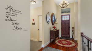 Entrance foyer with a chandelier, wood finished floors, and baseboards