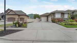 View of side of property with stone siding, stucco siding, a gate, a garage, and concrete driveway