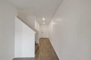 Hallway featuring stairs, wood finished floors, baseboards, and recessed lighting