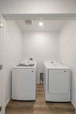 Laundry room featuring independent washer and dryer, wood finished floors, and baseboards