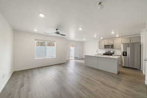 Kitchen with appliances with stainless steel finishes, a sink, light countertops, gray cabinets, and light wood finished floors