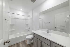 Full bath with wood finished floors, toilet, vanity, and shower / bath combination