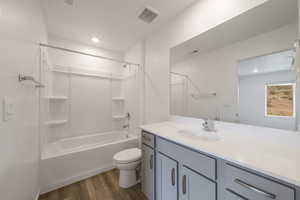 Bathroom featuring wood finished floors, vanity, toilet, bathing tub / shower combination, and recessed lighting