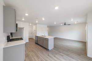 Kitchen featuring gray cabinets, a sink, stainless steel dishwasher, a ceiling fan, and gas stove
