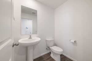 Bathroom featuring wood finished floors, toilet, and baseboards
