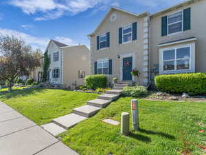 Townhome / multi-family property featuring a front yard and stucco siding