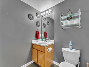 Bathroom featuring vanity, toilet, a textured ceiling, and baseboards