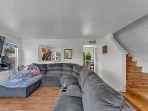 Living area with light wood-style floors, plenty of natural light, and stairway