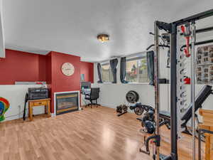 Exercise area featuring baseboards, wood finished floors, a glass covered fireplace, and a textured ceiling