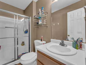 Full bath featuring vanity, toilet, and a shower stall
