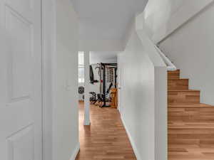 Hallway with light wood finished floors, baseboards, and stairway