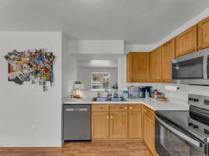 Kitchen with stainless steel appliances, a sink, light countertops, and light wood-type flooring