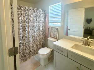 Full bath with vanity, toilet, and marble look tile flooring