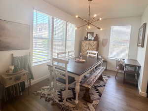 Dining space with a chandelier, dark wood-style flooring, and baseboards