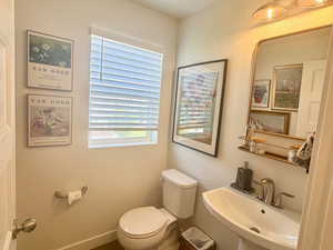 Bathroom with wood finished floors, toilet, and baseboards