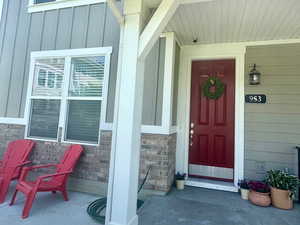 Doorway to property with board and batten siding, covered porch, and stone siding