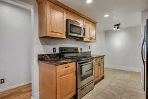 Kitchen featuring stainless steel appliances, recessed lighting, baseboards, and dark stone counters