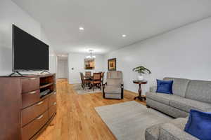 Living room featuring a chandelier, light wood-type flooring, recessed lighting, and baseboards