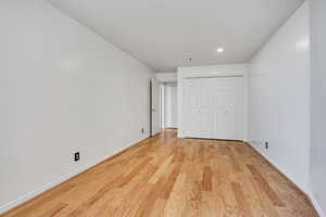 Unfurnished bedroom featuring light wood-style flooring, baseboards, recessed lighting, and a closet