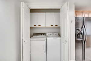 Laundry area featuring washing machine and dryer and cabinet space