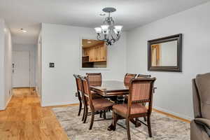 Dining area with light wood-style flooring, a chandelier, baseboards, and recessed lighting