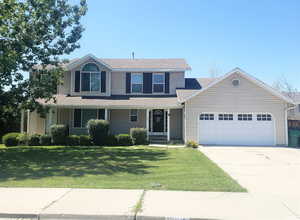 View of front of home featuring an attached garage, a front lawn, concrete driveway, roof with shingles, and a porch