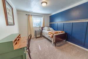 Carpeted bedroom with a textured ceiling and crown molding