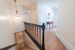Stairway with wood finished floors, recessed lighting, and baseboards
