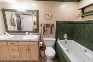 Bathroom with toilet, a tub with jets, and double vanity