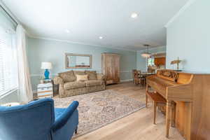 Living area with ornamental molding, light wood-type flooring, recessed lighting, and baseboards