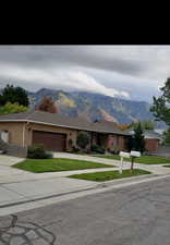 Ranch-style house featuring driveway, a mountain view, brick siding, and an attached garage