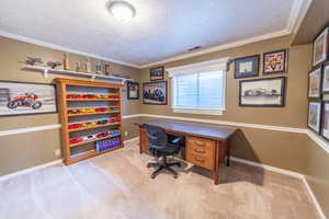 Carpeted home office featuring a textured ceiling, baseboards, and ornamental molding