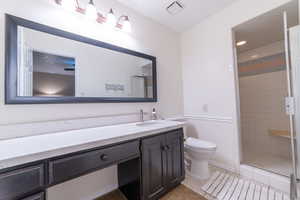 Full bathroom featuring toilet, vanity, a stall shower, and baseboards