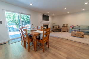 Dining space with light wood-style floors, a fireplace, recessed lighting, and baseboards