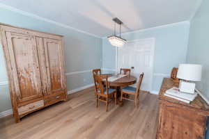 Dining space featuring light wood-type flooring, crown molding, and baseboards