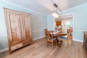 Dining area featuring light wood-style floors, ornamental molding, and baseboards