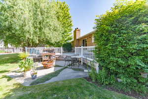 View of green lawn with a patio and a wooden deck