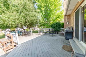 Wooden deck featuring outdoor dining space and a grill