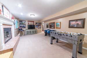 Rec room with carpet floors, a fireplace, and baseboards