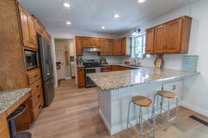 Kitchen featuring appliances with stainless steel finishes, under cabinet range hood, a sink, a peninsula, and recessed lighting