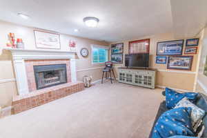 Living room with a fireplace, baseboards, carpet, and a textured ceiling