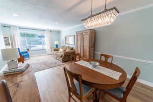 Dining area with wood finished floors, baseboards, recessed lighting, crown molding, and a chandelier