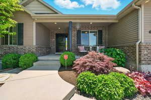 Entrance to property with brick siding and a porch