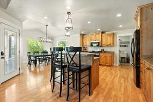 Kitchen featuring appliances with stainless steel finishes, a kitchen bar, light wood finished floors, a center island, and recessed lighting