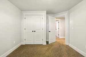 Unfurnished bedroom featuring carpet flooring, a closet, and baseboards