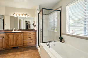 Bathroom featuring a shower stall, a garden tub, healthy amount of natural light, and vanity