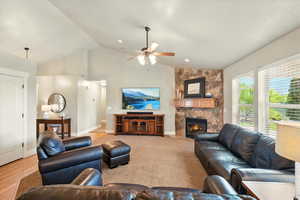Living room with lofted ceiling, ceiling fan, a fireplace, and baseboards