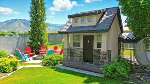Rear view of house featuring a mountain view, stucco siding, a fire pit, stone siding, and an outdoor structure
