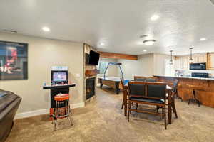 Dining room with light carpet, recessed lighting, a stone fireplace, a textured ceiling, and baseboards