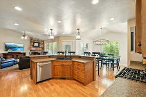 Kitchen with vaulted ceiling, a sink, dishwasher, a breakfast bar, and light wood-type flooring
